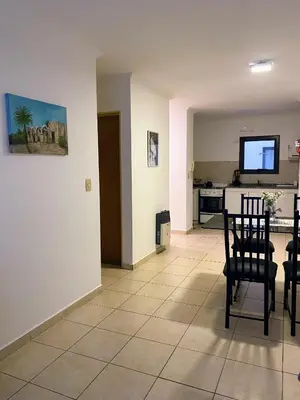 a living room with a table and chairs and a kitchen at Calidez in Villa Carlos Paz