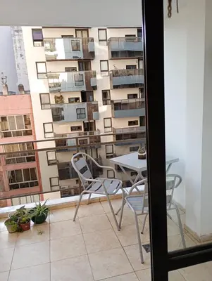 a table and chairs on a balcony with a building at Apart salguero in Cordoba