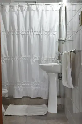a bathroom with a white shower curtain and a sink at Cabañas Rayuela y otros cuentos in Santa Rosa de Calamuchita