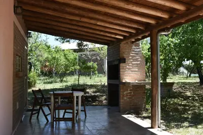 a patio with a table and chairs under a wooden pergola at Cabañas Rayuela y otros cuentos in Santa Rosa de Calamuchita