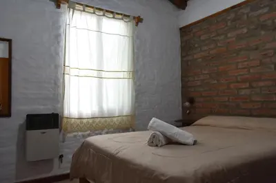 a bedroom with a bed and a brick wall at Cabañas Rayuela y otros cuentos in Santa Rosa de Calamuchita