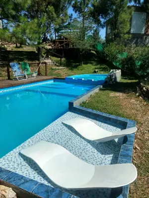 a swimming pool with two white chairs in a yard at Terra Nostra in Cordoba
