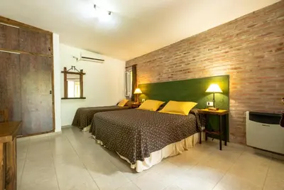 a bedroom with two beds and a brick wall at Los Sauces Posada in Nono