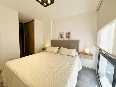 a bedroom with a white bed with two lamps and a window at PASEO QUATTRO in Villa Carlos Paz