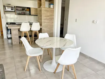 a glass table and white chairs in a kitchen at PASEO QUATTRO in Villa Carlos Paz
