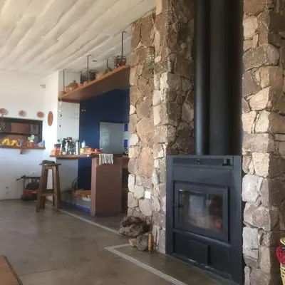 a living room with a stone fireplace in a kitchen at LUMAFACA in La Población