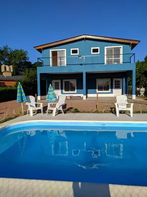 a blue house with chairs and a swimming pool at Complejo Cielo Azul in Villa Rumipal