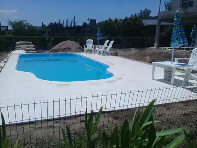 a swimming pool with a table and chairs next to it at Complejo Cielo Azul in Villa Rumipal