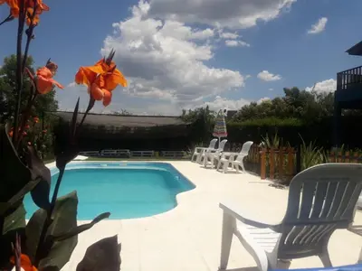 a swimming pool with two chairs and a table at Complejo Cielo Azul in Villa Rumipal