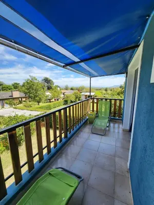 a balcony with green chairs and a blue awning at Complejo Cielo Azul in Villa Rumipal