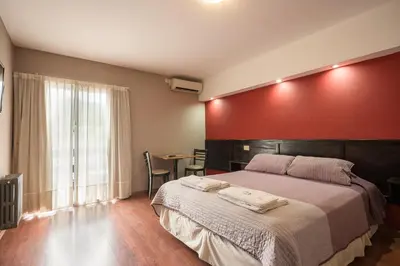 a bedroom with a large bed with a red wall at Aguas Claras Hosteria in Santa Rosa de Calamuchita