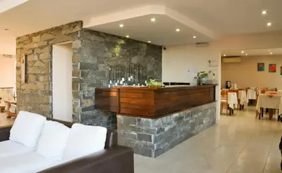 a restaurant with a stone wall with a bar at Aguas Claras Hosteria in Santa Rosa de Calamuchita