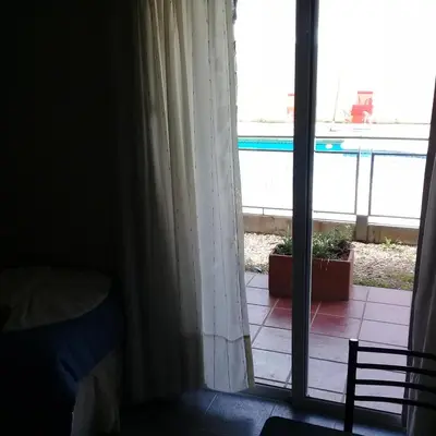 a bedroom with a window with a view of a patio at Aguas Claras Hosteria in Santa Rosa de Calamuchita