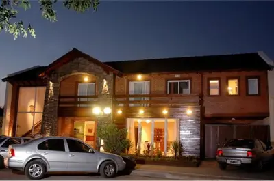a house with two cars parked in front of it at Aguas Claras Hosteria in Santa Rosa de Calamuchita