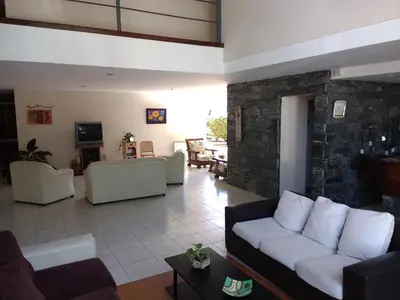 a living room with white couches and a stone wall at Aguas Claras Hosteria in Santa Rosa de Calamuchita