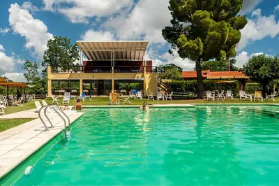 a swimming pool with people in the water at Balcón del Río, Hotel de Campo y Cabañas in Mina Clavero