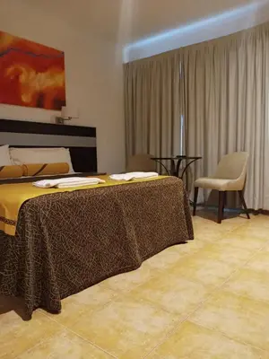 a bedroom with a bed with a table and a chair at Balcón del Río, Hotel de Campo y Cabañas in Mina Clavero