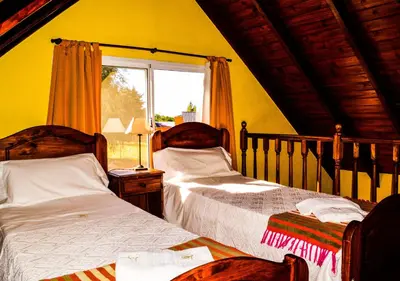 a bedroom with two beds and a window at Cabañas Brisas del Cerro in Los Reartes