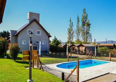 a swimming pool in a yard with a house at Cabañas Brisas del Cerro in Los Reartes
