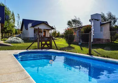 a swimming pool with a playground and a house at Cabañas Brisas del Cerro in Los Reartes