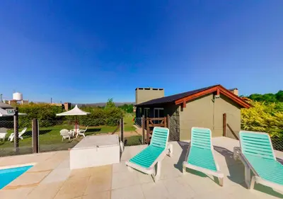 a patio with two blue chairs and a pool at Cabañas Brisas del Cerro in Los Reartes