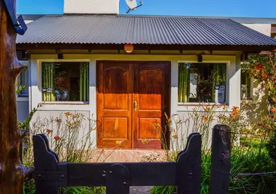a house with a wooden door in front of it at Cabañas Brisas del Cerro in Los Reartes