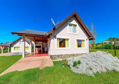 a white house with a brown roof at Cabañas Brisas del Cerro in Los Reartes