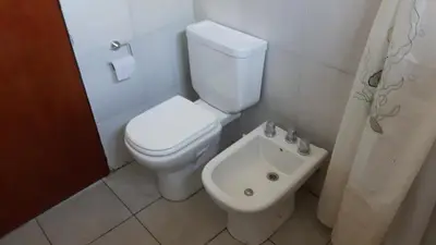 a bathroom with a white toilet and a sink at Piscu Yaco in Santa Rosa de Calamuchita