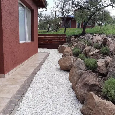 a garden with rocks and a building with a window at Piscu Yaco in Santa Rosa de Calamuchita