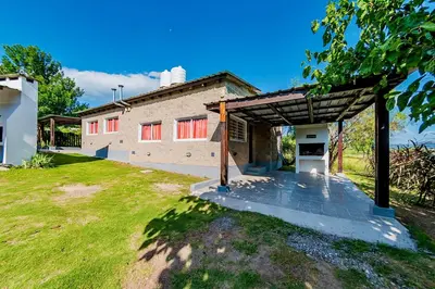 a building with a pavilion in front of a yard at La Querencia in Villa Carlos Paz