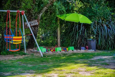 a playground with a swing and an umbrella at La Querencia in Villa Carlos Paz
