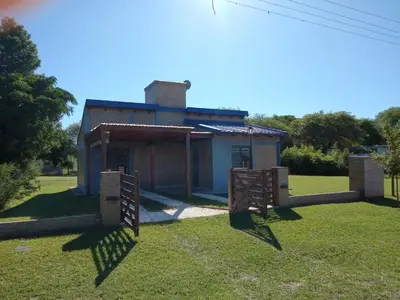 a small house with a gate in the grass at Cabaña Azul in Villa Anizacate