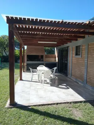 a patio with a table and chairs under a pergola at Cabaña Azul in Villa Anizacate