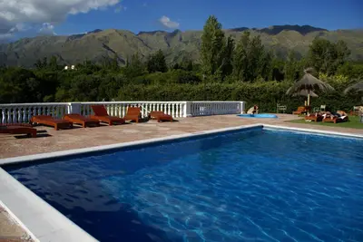 a swimming pool with chairs and mountains in the background at El Cortijo Apart - Hotel in Merlo
