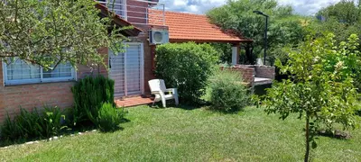 a house with a white chair sitting in the yard at Ayres Serranos in Merlo