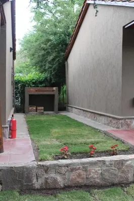 a yard with red flowers in a flower bed next to a building at Mont Blanc in Villa General Belgrano