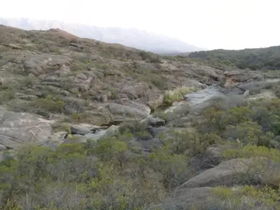 a river in the middle of a rocky mountain at Cabaña de Montaña, La Casita Mina Clavero CBA in Mina Clavero
