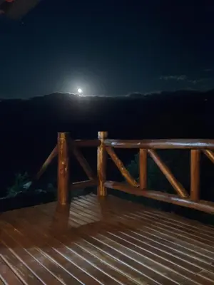 a moonrise over a wooden deck at night at Cabaña de Montaña, La Casita Mina Clavero CBA in Mina Clavero