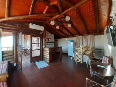 a large living room with wooden ceilings and a table at Cabaña de Montaña, La Casita Mina Clavero CBA in Mina Clavero