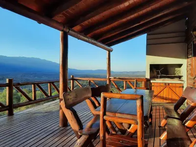 a deck with chairs and a kitchen on a house at Cabaña de Montaña, La Casita Mina Clavero CBA in Mina Clavero