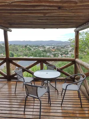 a table and chairs on a wooden deck with a view at Cabañas Los Álamos in Villa Carlos Paz