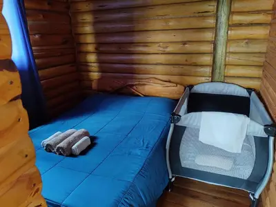 a bed in a room with a wooden wall at Cabañas Los Álamos in Villa Carlos Paz