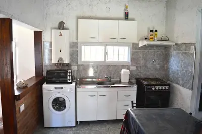 a small kitchen with a stove and a washer at Mini Complejo Familiar Roque in Mina Clavero
