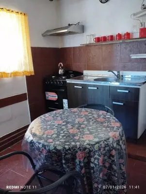 a kitchen with a table and a sink and a stove at Mini Complejo Familiar Roque in Mina Clavero