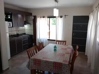a dining room with a table and a kitchen at Complejo Cerro Negro VGB in Villa General Belgrano