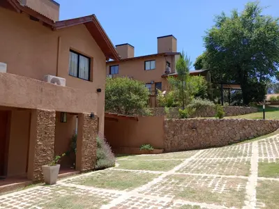 a house with a stone wall next to a driveway at Complejo Cerro Negro VGB in Villa General Belgrano
