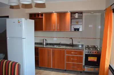 a kitchen with wooden cabinets and a white refrigerator at Complejo Cerro Negro VGB in Villa General Belgrano