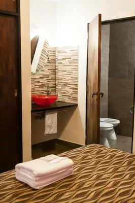 a bathroom with a bed and a sink and a toilet at Posada Alpenrose Neu in Villa Carlos Paz