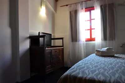 a bedroom with a bed and a television and a window at Posada Alpenrose Neu in Villa Carlos Paz