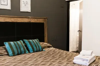 a bed with blue and green pillows in a bedroom at Posada Alpenrose Neu in Villa Carlos Paz